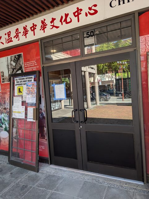 Finished Chinatown entrance doors with new glass, viewed along the storefront