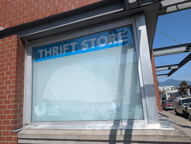Cracked storefront window at a thrift store awaiting replacement
