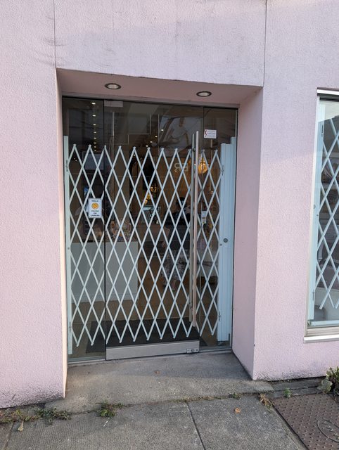 Folding security gate closed across a recessed shop entrance