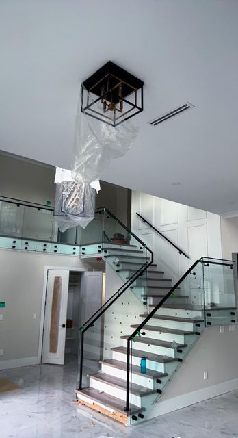Glass railing with black handrail on floating stairs