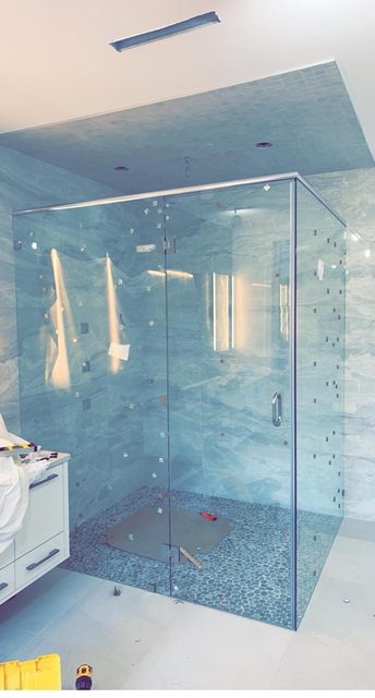 Frameless corner shower enclosure against blue marble tile