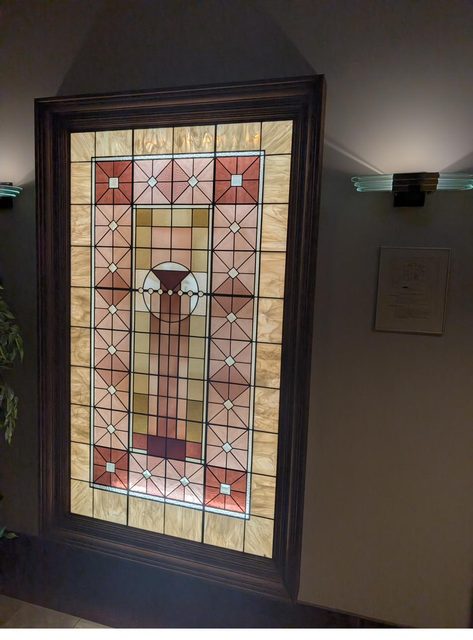 Backlit leaded art glass panel restored and reframed in a home entryway