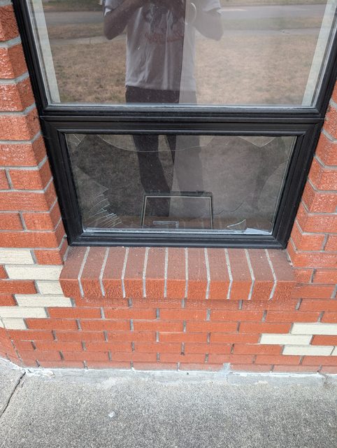 Cracked window at the corner of a brick building before replacement
